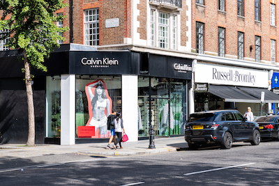 Calvin Klein store in Hong Kong with large-scale visuals, glass façade, and shoppers walking along a busy street.