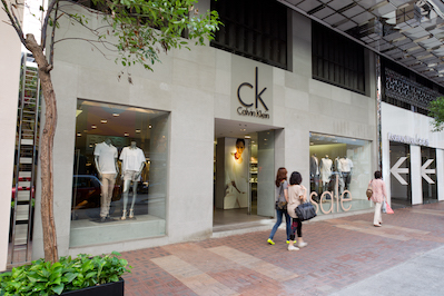Exterior of Calvin Klein Underwear retail store with signage, glass doors, and city buildings in the background.