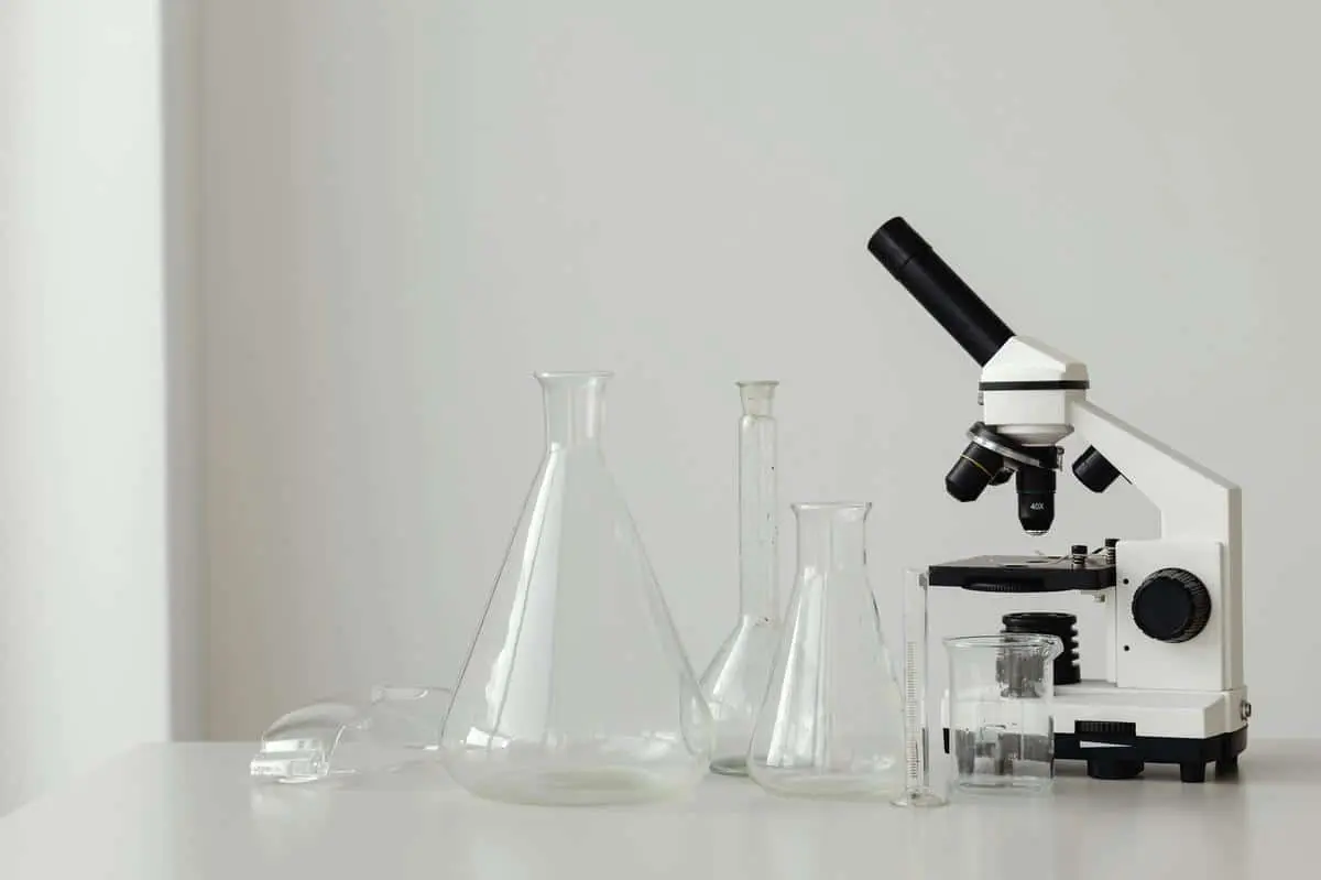 Glass beakers and a microscope on a lab table representing chemical product testing and KKDIK compliance